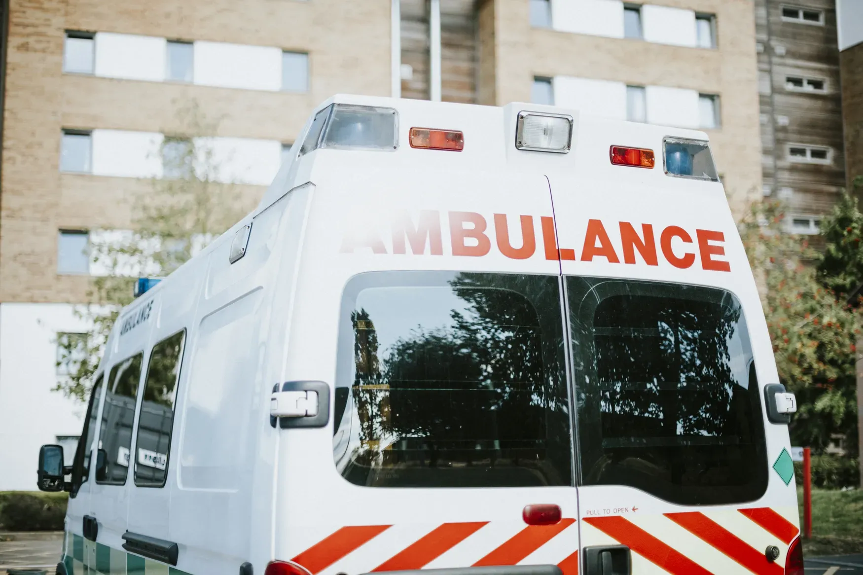 Arrière d'une ambulance blanche garée devant un immeuble