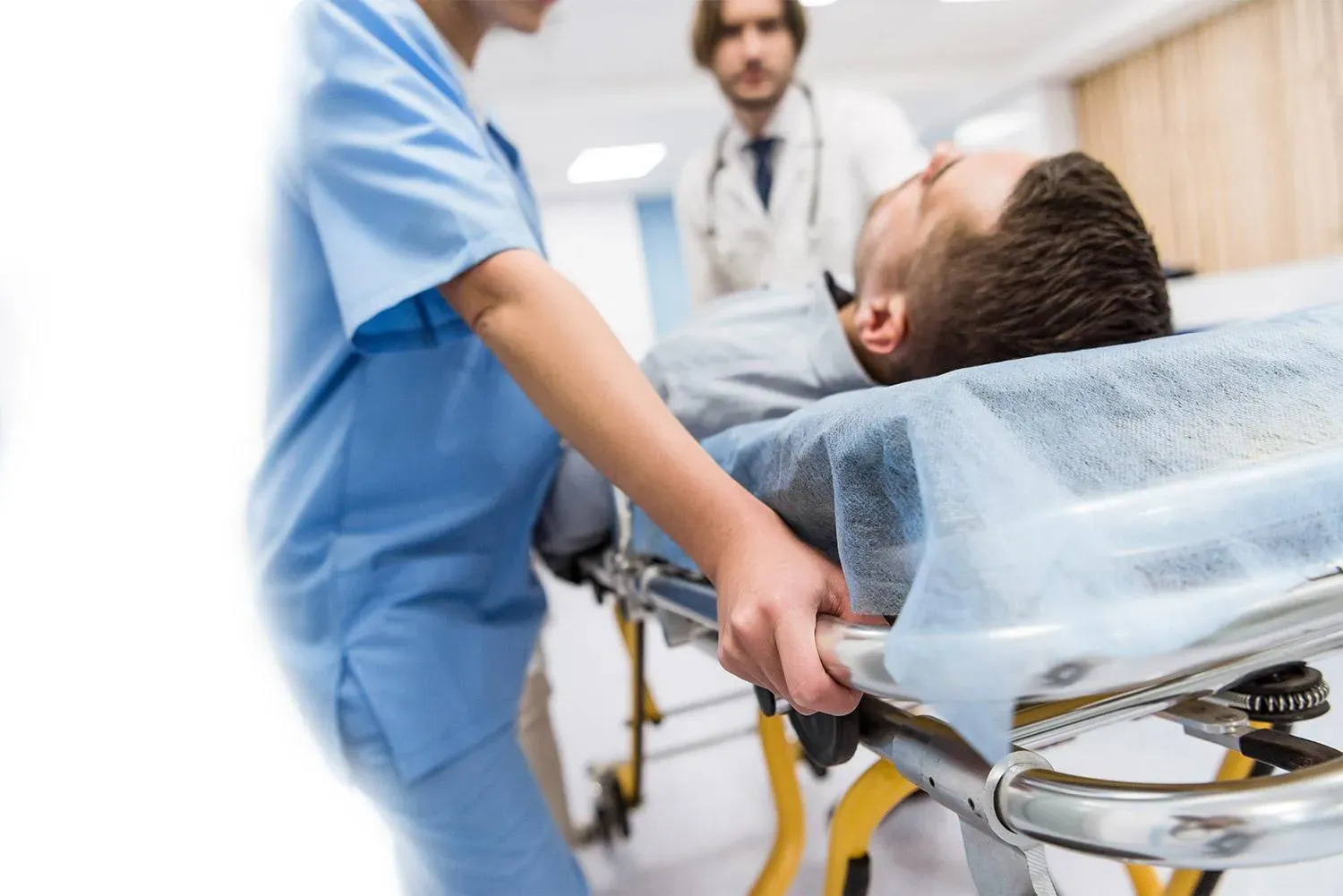 Soignante poussant un brancard où un patient est allongé, un médecin à ses côtés