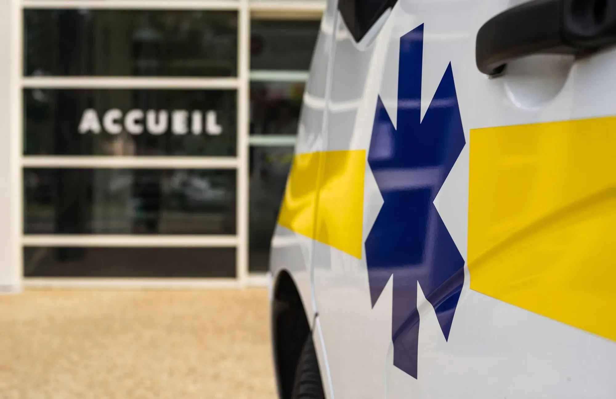 Flanc d'une ambulance avec l'étoile de vie devant l'entrée d'un bâtiment