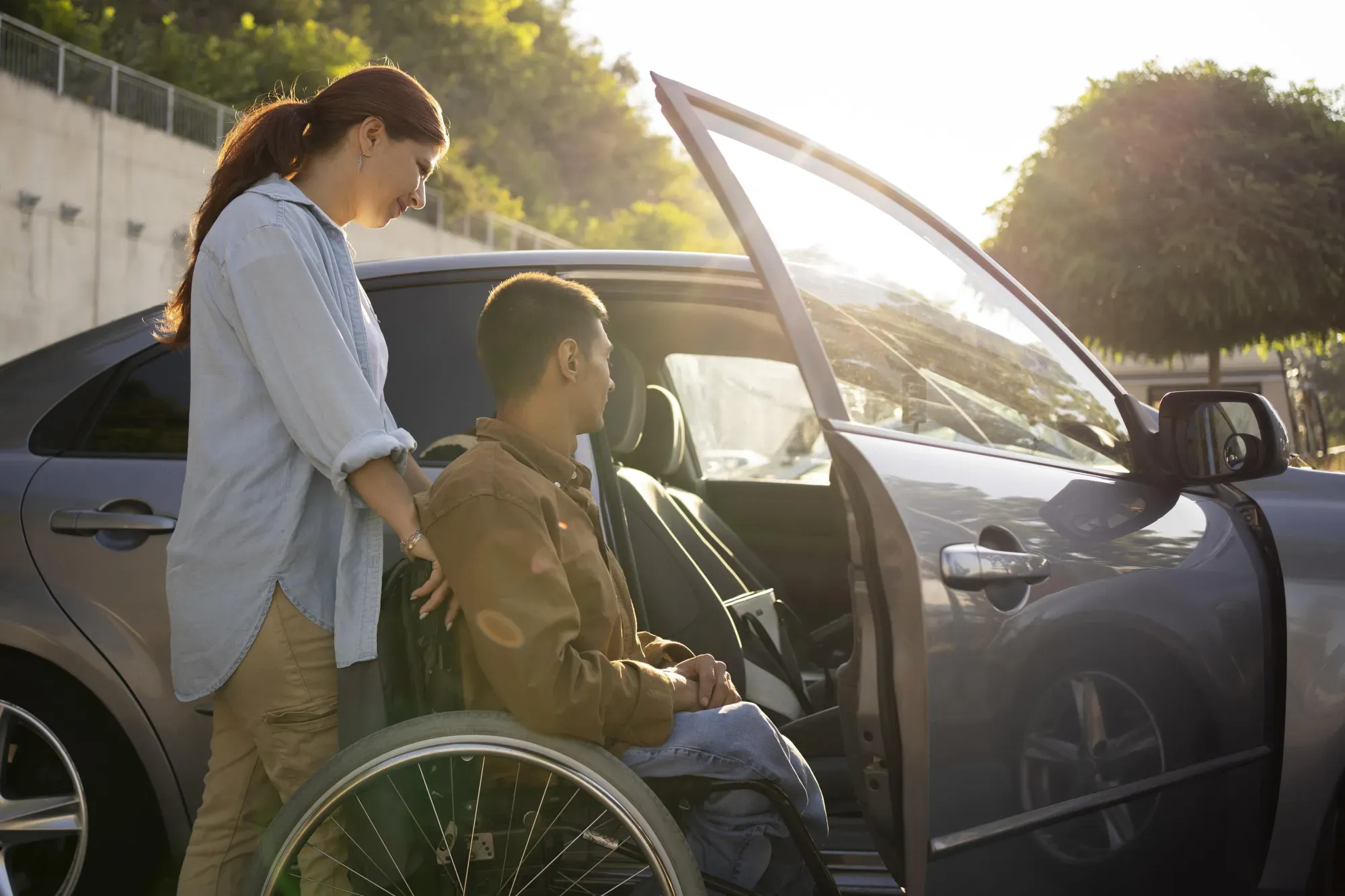 Accompagnatrice aidant une personne en fauteuil roulant à monter dans une voiture