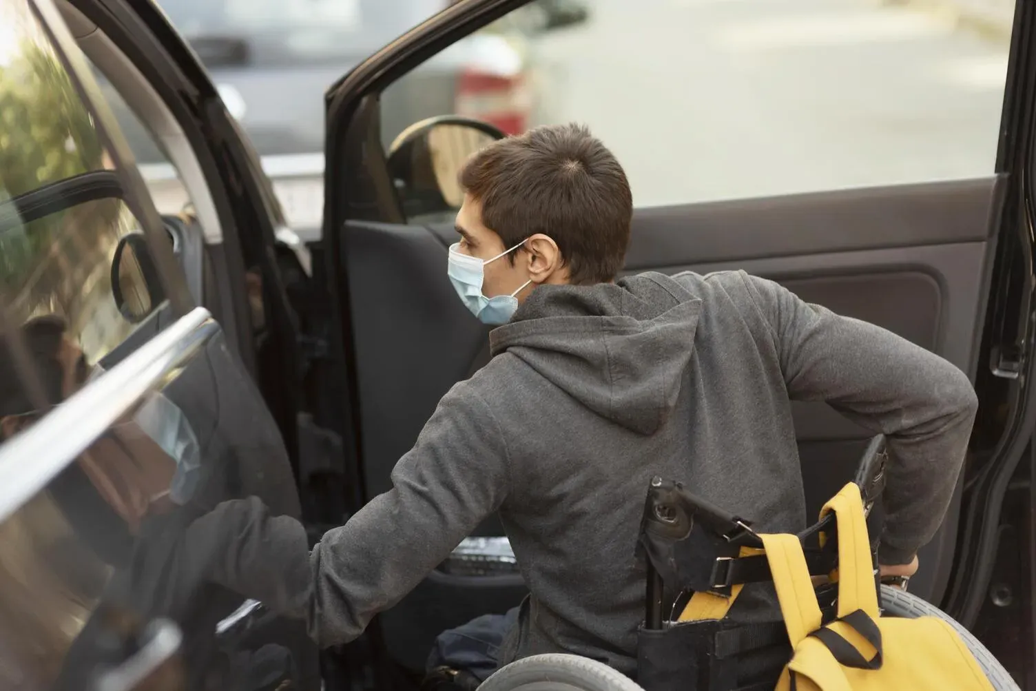 Personne masquée montant dans un véhicule depuis son fauteuil roulant