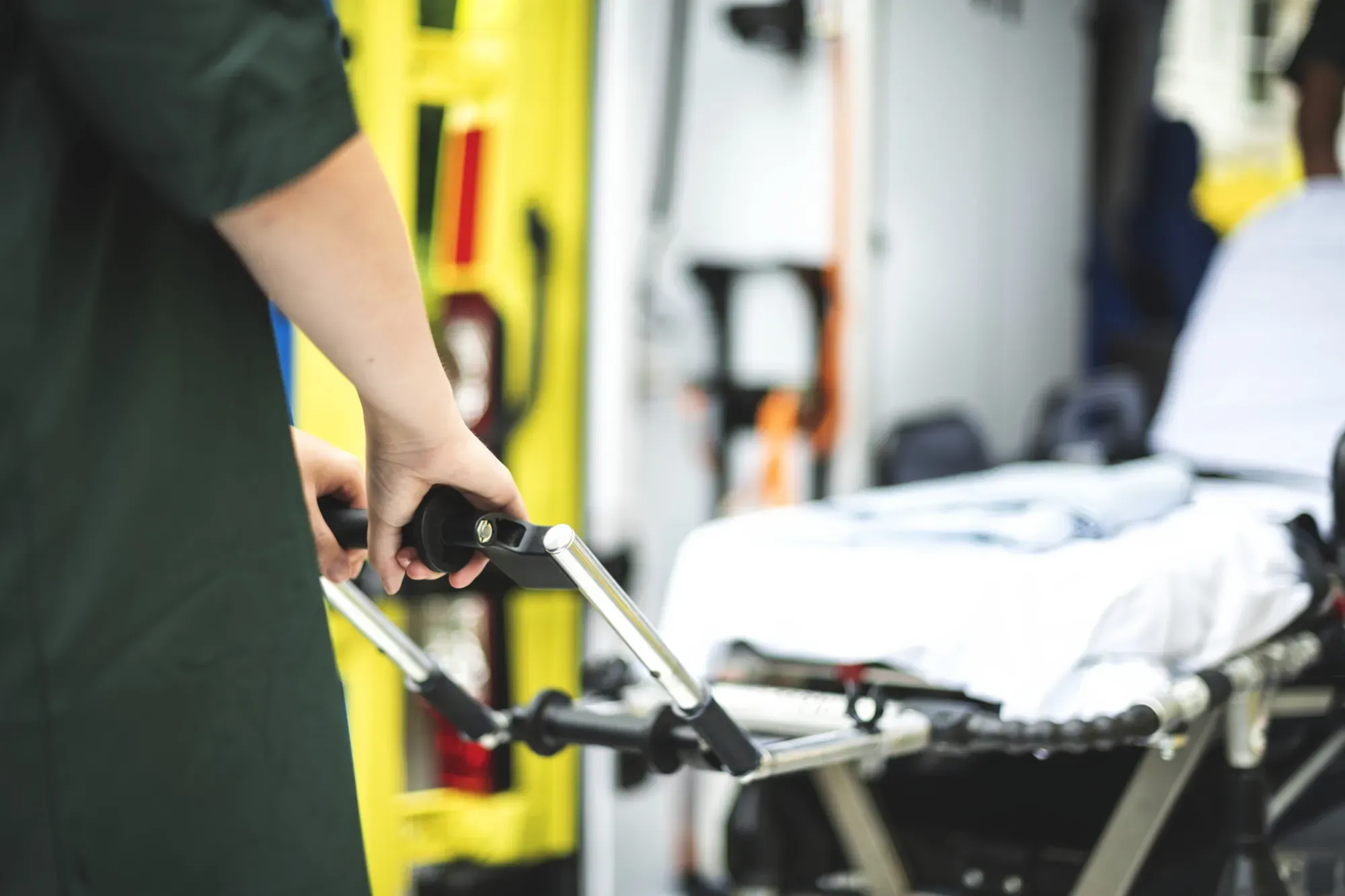 Ambulancier manœuvrant un brancard devant une ambulance