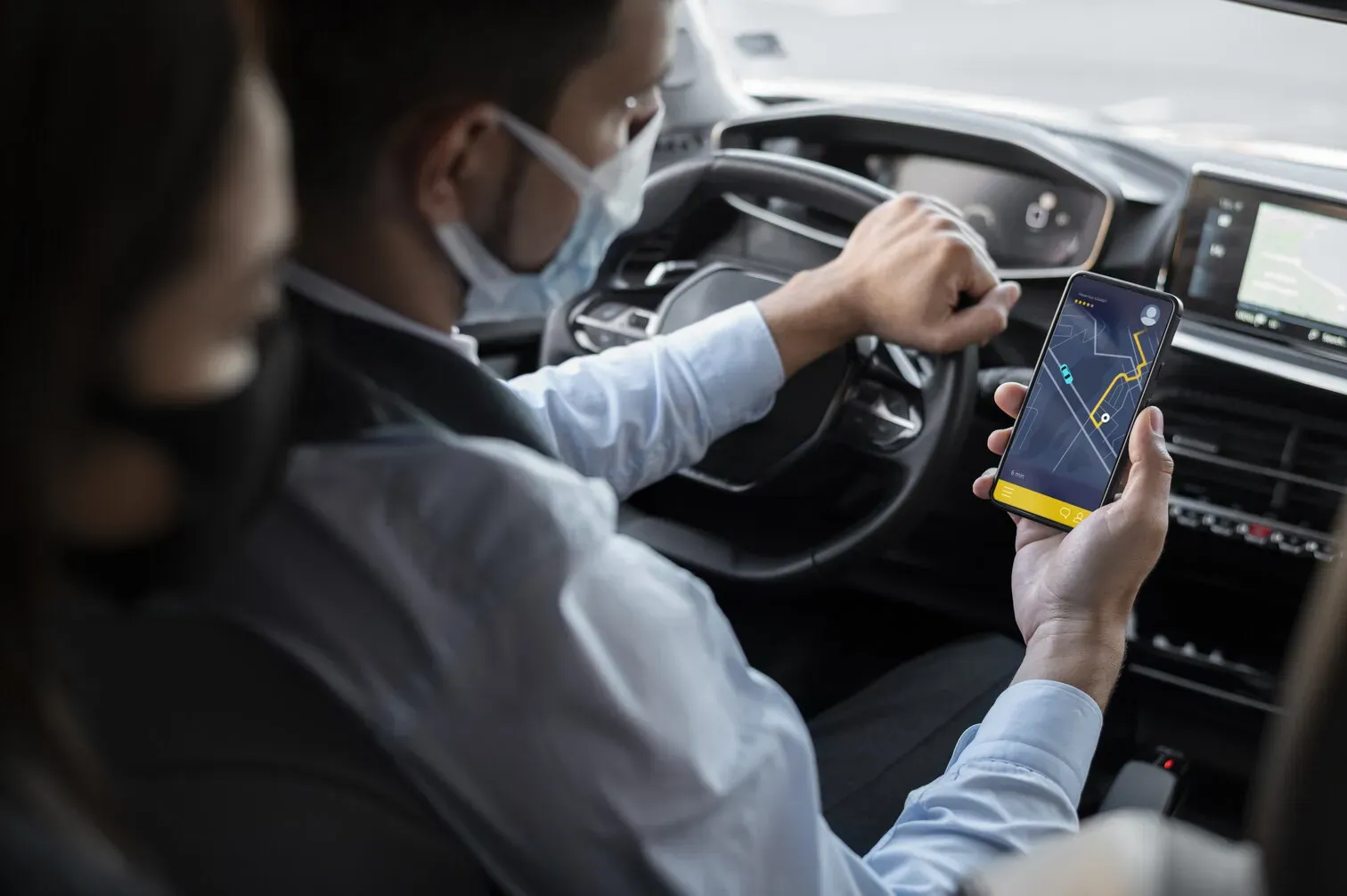 Chauffeur masqué au volant consultant son téléphone